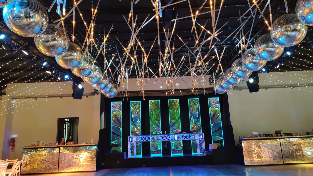 Salón con luces colgantes, esferas y pantallas verticales