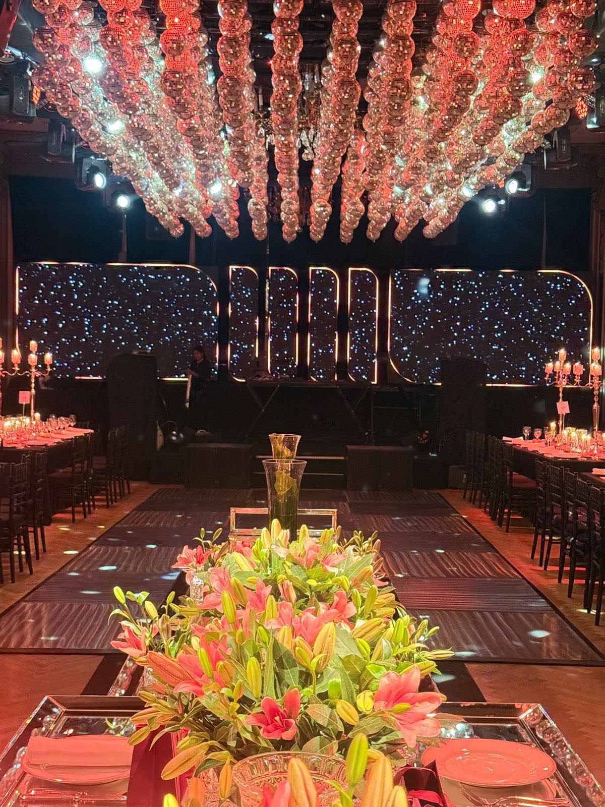 Casamiento con techo floral iluminado y mesas decoradas