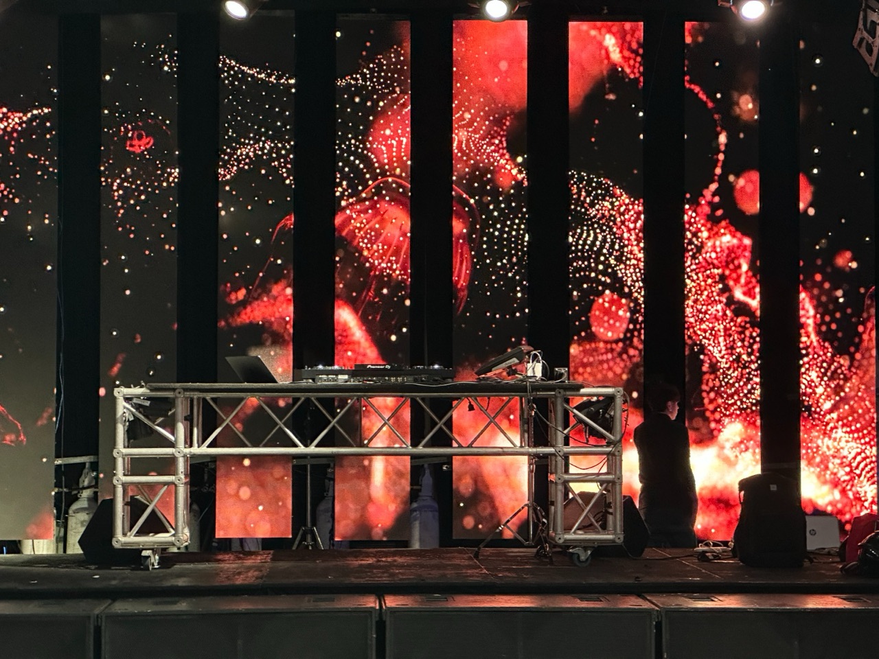 Pantallas LED con visuales rojos detrás de una cabina de truss